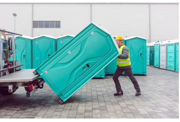 Crew member loading a portable restroom unit onto a delivery trailer